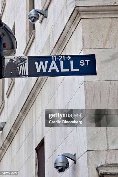 Security cameras hang on the exterior of the New York Stock Exchange in the background of a Wall Street sign in New York, U.S., on Monday, May 10,...