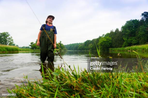 ein junger fischer auf dem fluss in den frühen morgenstunden - waders stock-fotos und bilder