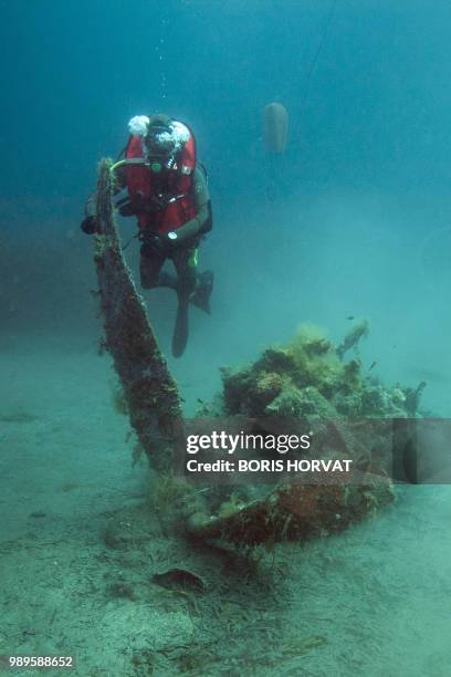 French military diver member of the FS Pluton M622 navy de-mining ship, swims on July 2 above the wreck of an USAAF P-47 Thunderbolt US fighter...