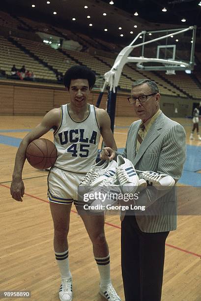 Portrait of UCLA Henry Bibby with head coach John Wooden holding sneakers at Pauley Pavilion. Los Angeles, CA CREDIT: George Long