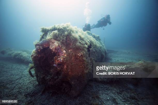French military diver member of the FS Pluton M622 navy de-mining ship, swims on July 2 above the wreck of an USAAF P-47 Thunderbolt US fighter...