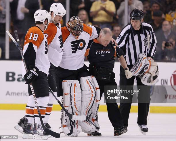 Brian Boucher of the Philadelphia Flyers is helped off the ice by teammates Chris Pronger and Mike Richards after he was injured in the second period...