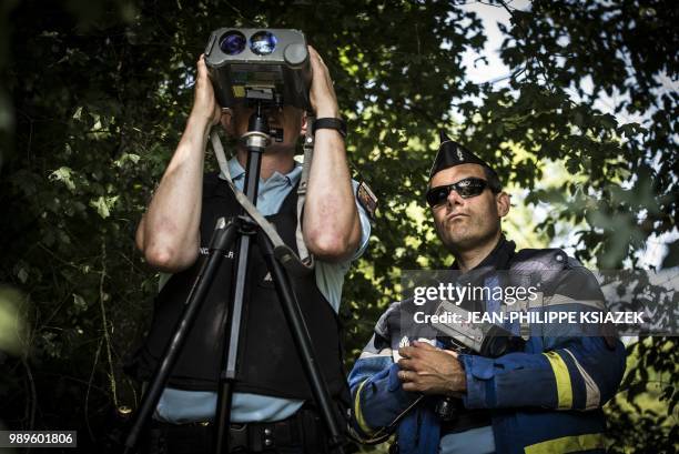 French gendarme looks through a speed camera during an educational speed control on a secondary road with a newly imposed speed limit of 80 kmph, on...