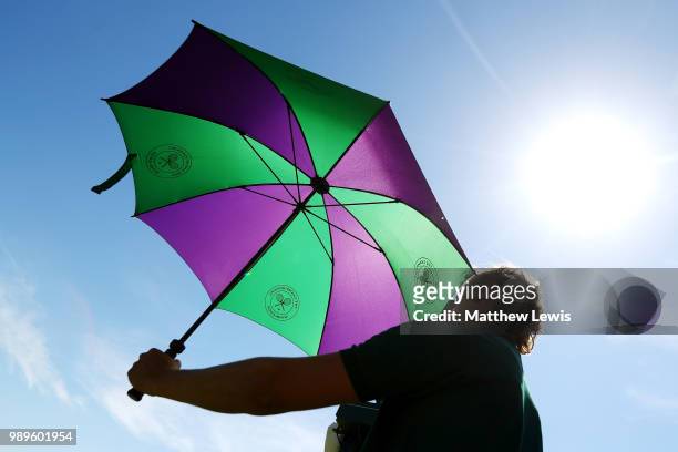 Court attendant holds an umbrella on day one of the Wimbledon Lawn Tennis Championships at All England Lawn Tennis and Croquet Club on July 2, 2018...