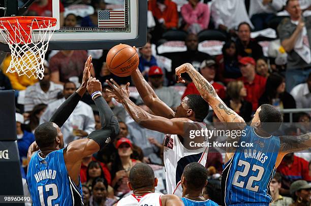 Joe Johnson of the Atlanta Hawks drives to the basket against Dwight Howard and Matt Barnes of the Orlando Magic during Game Four of the Eastern...