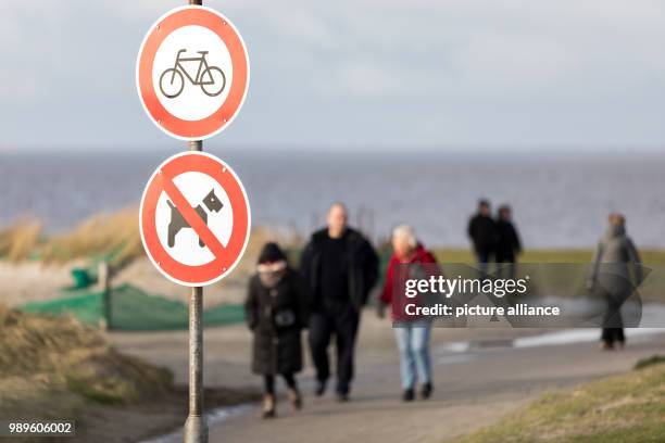 People walk in sunshine along the beach of Norden in Norddeich, Germany, 02 December 2018. Photo: Mohssen Assanimoghaddam/dpa