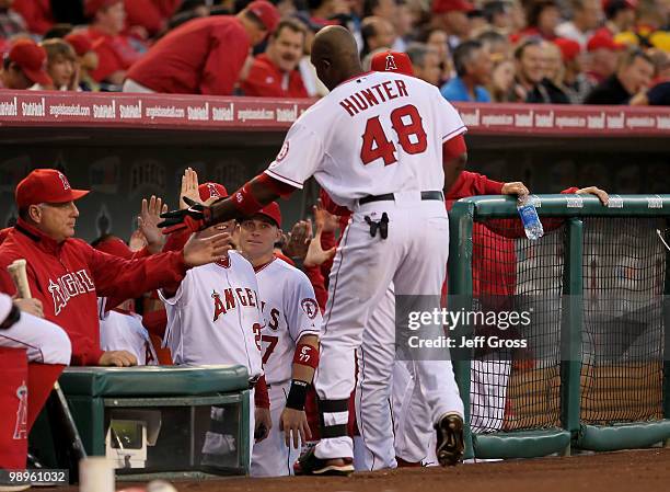 Torii Hunter of the Los Angeles Angels of Anaheim receives high fives from the dugout after hitting a sacrifice fly that scored Erick Aybar in the...