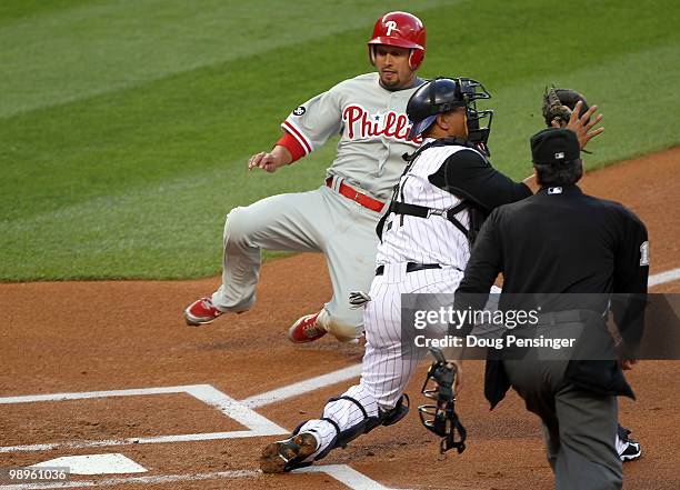 Shane Victorino of the Philadelphia Phillies slides safely into home to score in the first inning as catcher Miguel Olivo of the Colorado Rockies...