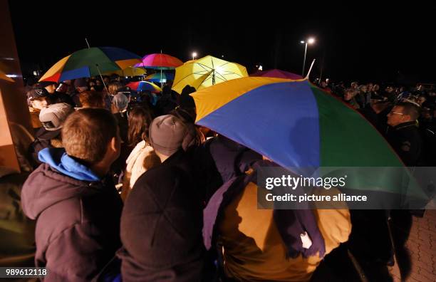 People holding umbrellas stand in front of a drug store after a funeral march for a 15-year-old girl, who was stabbed by her boyfriend in the store...