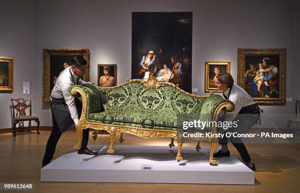 Gallery assistants adjust a George III Giltwood sofa, designed by Robert Adam and made by Thomas Chippendale, during a photocall for Christie's...