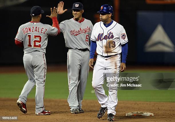 Alex Cora of the New York Mets looks on as Alberto Gonzalez and Ian Desmond of the Washington Nationals celebrate after the final out of the game on...