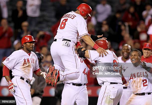 Kendry Morales of the Los Angeles Angels of Anaheim leaps on to Juan Rivera after Rivera drove in Morales with a sacrifice fly in the 12th inning...