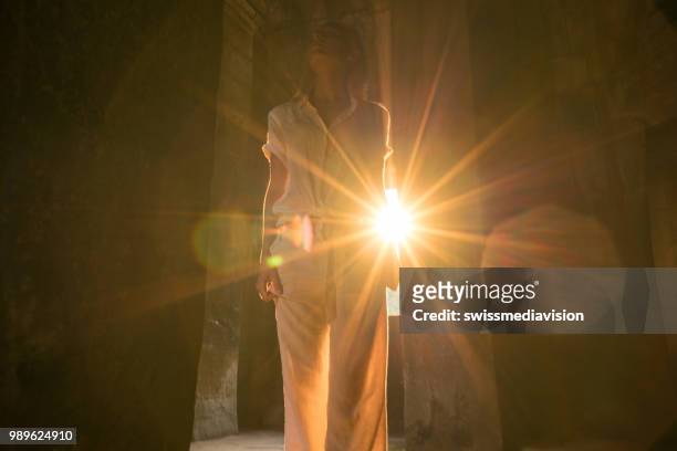 view of tourist traveler exploring ancient temple at sunset, sunbeam passing through window. people travel exploration concept - sun rays through window stock pictures, royalty-free photos & images