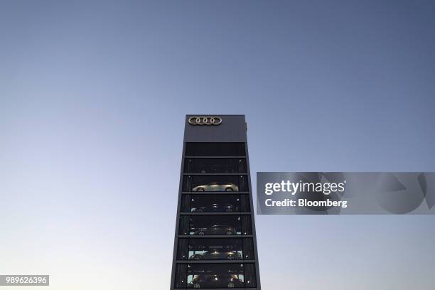 New Audi AG automobiles sit illuminated in a glass display tower at the automaker's showroom in Berlin, Germany, on Tuesday, June 19, 2018. For BMW...