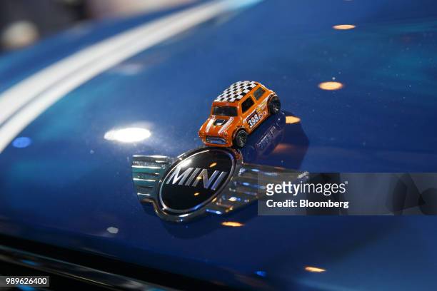 Toy car in the likeness of a MINI is placed over the badge of the Bayerische Motoren Werke AG MINI Countryman compact sports utility vehicle on...