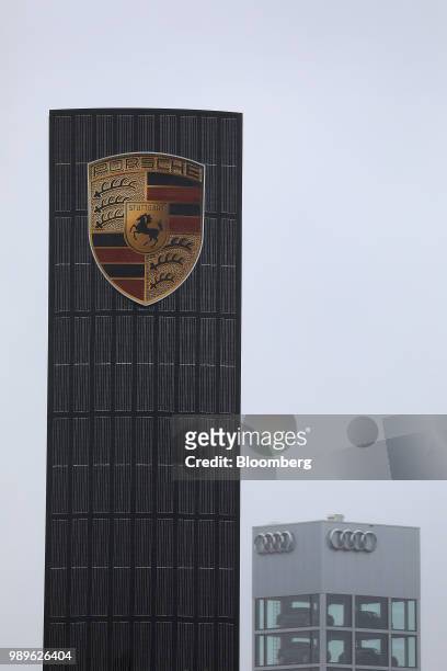 The Porsche AG badge sits on a sign as automobiles sit in glass tower at an Audi AG showroom beyond in Berlin, Germany, on Wednesday, July 26, 2017....