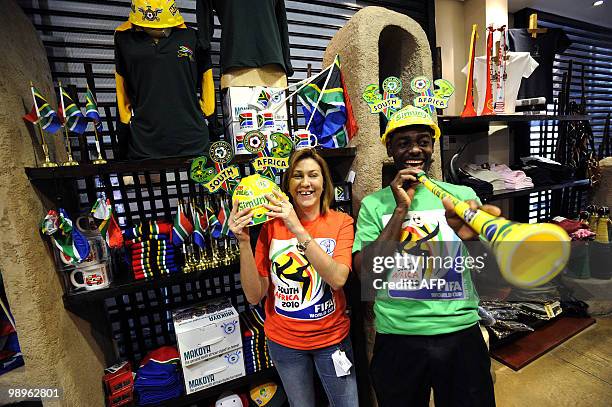 Employees in a shop of the Kruger Mpumalanga International airport blow into a vuvuzela and hold up a helmet at the Kruger Mpumalanga International...