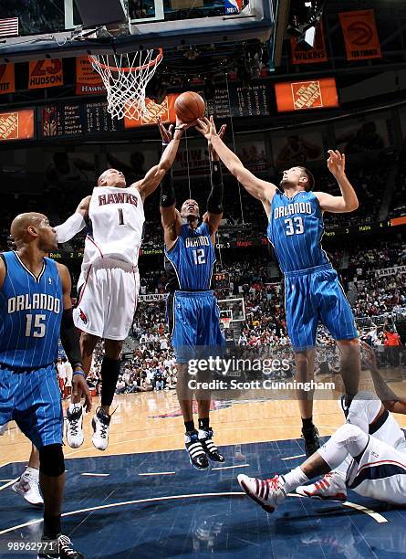 Maurice Evans of the Atlanta Hawks rebounds against Ryan Anderson and Dwight Howard of the Orlando Magic in Game Four of the Eastern Conference...