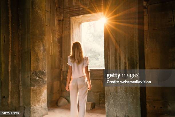 view of tourist traveler exploring ancient temple at sunset, sunbeam passing through window. people travel exploration concept - sun rays through window stock pictures, royalty-free photos & images