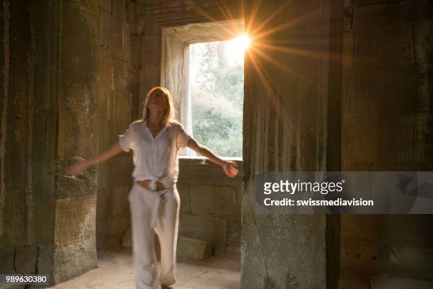 view of tourist traveler exploring ancient temple at sunset, sunbeam passing through window. people travel exploration concept - sun rays through window stock pictures, royalty-free photos & images