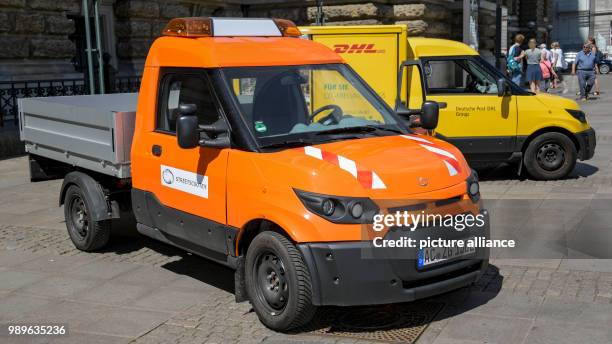 July 2018, Germany, Hamburg: Vehicles from the DHL subsidiary 'Streetscooter' standing on the town hall square. The Deutsche Post DHL Group and...