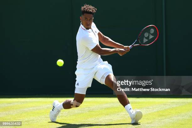 Michael Mmoh of The United States returns to Gilles Muller of Luxembourg during their Men's Singles first round match on day one of the Wimbledon...
