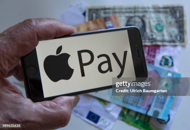 Symbol photo on the topic pay with the smartphone. The picture shows the Apple Pay logo on a smartphone display. A hand holds the smartphone over...