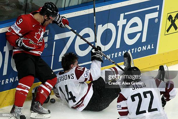 Janis Andersons of Latvia loses his helmet after being challenged by Steve Downie of Canada during the IIHF World Championship group B match between...