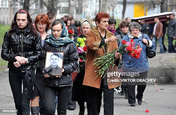 People carry flowers and a picture of 50-year-old Fedor Akintiyev, miner killed at the Raspadskaya mine, during a funeral ceremony in Mezhdurechensk,...