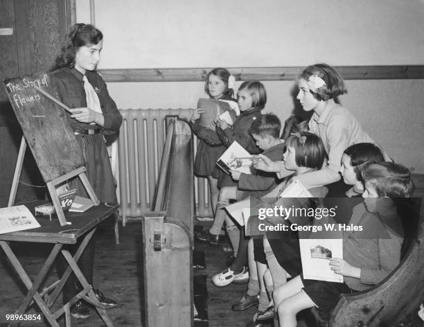 Girl Guide Sheila Burr, aged 14, teaches a class of infants at Claybury Park, Ilford, Essex, during World War II, 6th November 1939. She is assisted...