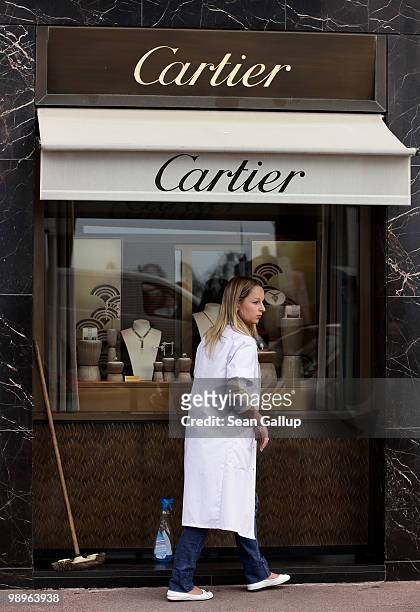Young woman cleans the display windows of a Cartier luxury jewellery store prior to the annual film festival on May 11, 2010 in Cannes, France. The...
