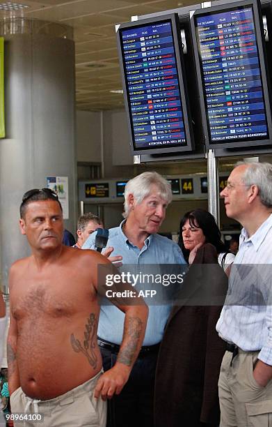 Passengers wait near information screens displaying canceled flighst at the Reina Sofial airport on the touristic Spanish Canary Island of Tenerife...