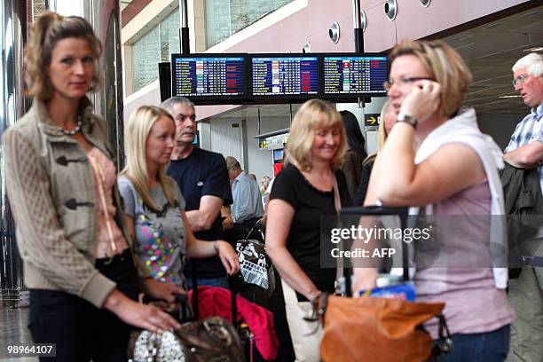 Passengers wait near information screens displaying cancelled flights at the Reina Sofial airport on the touristic Spanish Canary Island of Tenerife...