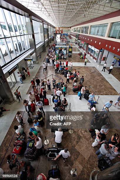 Passengers wait near information screens displaying cancelled flights at the Reina Sofial airport on the touristic Spanish Canary Island of Tenerife...