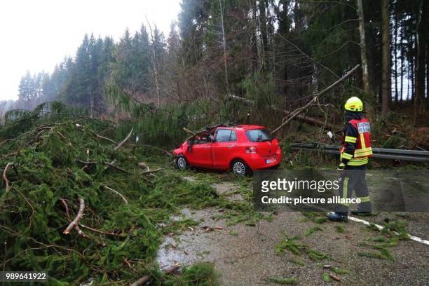 Fire fighters rescue a red car which was stuck in between fallen trees on the main road B19 near Fischen, Germany, 03 January 2018. The B19 was...