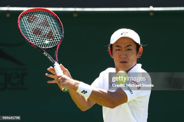 Yoshihito Nishioka of Japan returns to Marin Cilic of Croatia during their Men's Singles first round match on day one of the Wimbledon Lawn Tennis...