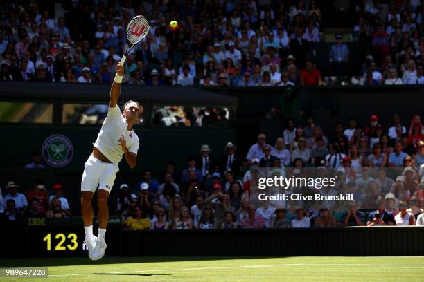 Roger Federer of Switzerland serves to Dusan Lajovic of Serbia during their Men's Singles first round match on day one of the Wimbledon Lawn Tennis...