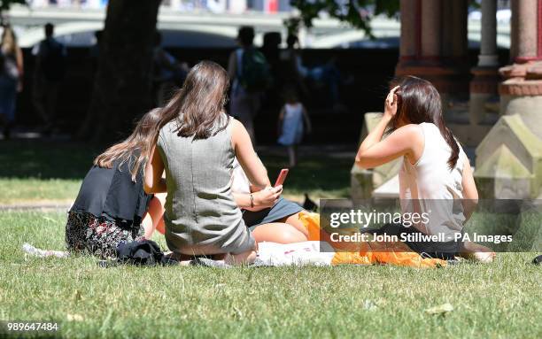 Office workers enjoy the hot sunny weather while taking their lunch breaks in Victoria Tower Gardens, Westminster central London.