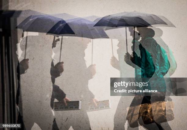 Dpatop - Pedestrians walks past each other holding umbrellas in front of a shopping centre in Frankfurt, Germany, 4 January 2018. The warer levels in...