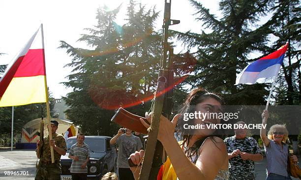 Female resident of Tskhinvali fires in the air with a kalashnikov machine gun as South Ossetians celebrate the recognition of their country's...