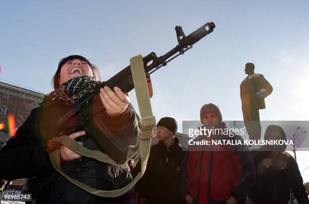 Girl bursts into laughter as she holds a Kalashnikov submachine gun during a rally devoted to the national holiday celebration, the Day of the...