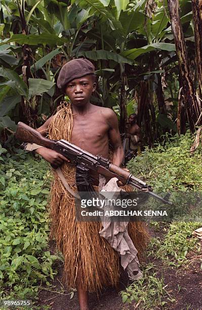 Zairian Mai-Mai militia rebel child soldier holding his AK-47 Kalashnikov assault rifle 01 December 1996 as he and others head for fighting Zaire...