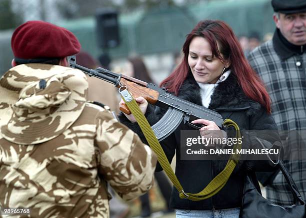 Woman looks at the weapon of a soldier from the 495 Infantry Batalion during an official ceremony prior to their deployment to Iraq to support the...