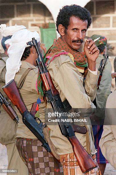 Militiaman, partisan of Yemen Socialist Party senior leader Abdul Fattah Ismail, smokes, with his kalashnikov, in an abandoned post of President Ali...