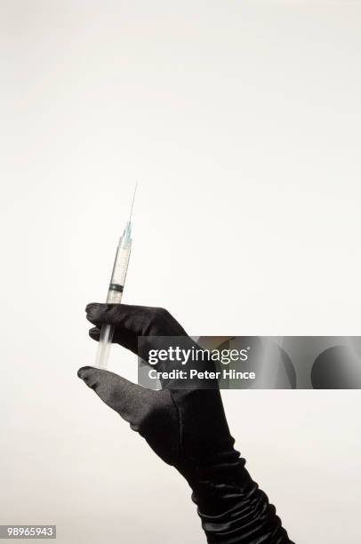 gloved hand with hypodermic syringe - formal glove stock pictures, royalty-free photos & images