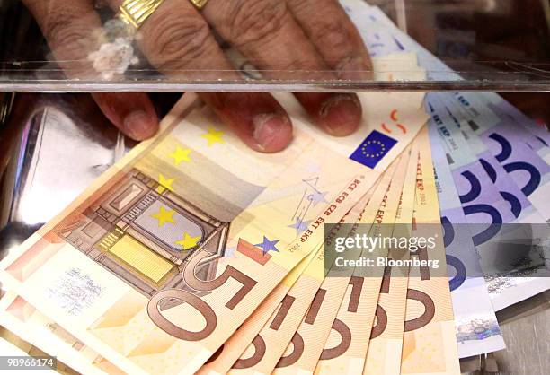 Cashier at a money exchange holds a stack of euro notes in London, U.K., on Tuesday, May 11, 2010. The euro lost all of yesterday's gains on concern...