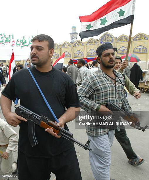Shiite Iraqi militiamen guard the area around Imam al-Kazem shrine as thousands of worshippers marched after the weekly Friday prayer, many carrying...