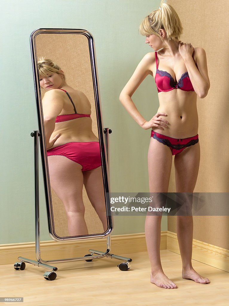 Anorexic woman looking at bum in mirror
