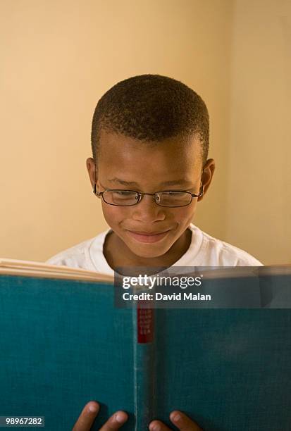 boy (8-9) smiling while reading book, st francis bay, sea vista, eastern cape province, south africa - malan stock-fotos und bilder