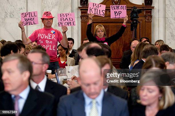 Protestors hold signs behind Lamar McKay, president and chairman of BP America Inc., center, during a Senate Energy and Natural Resources Committee...